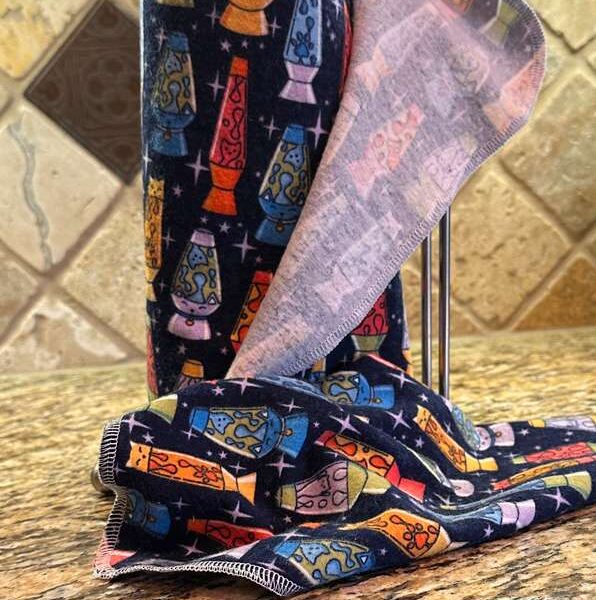 Muss Busters reusable towels on a paper towel holder in kitchen with one towel pulled off wiping a spill